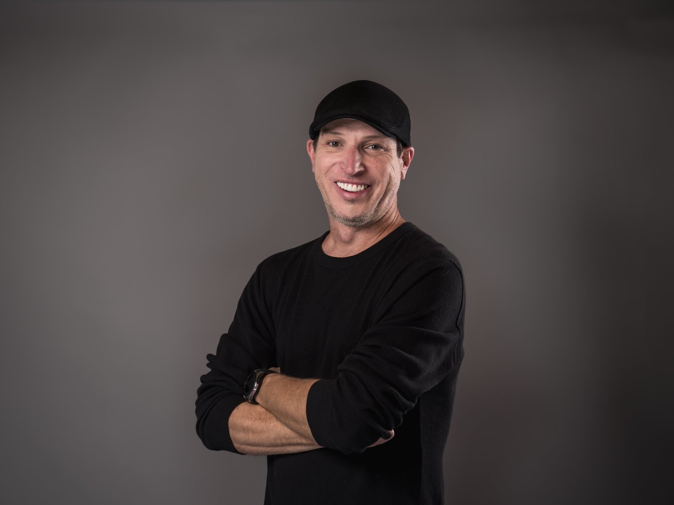 John Hilder smiling in a black cap and shirt